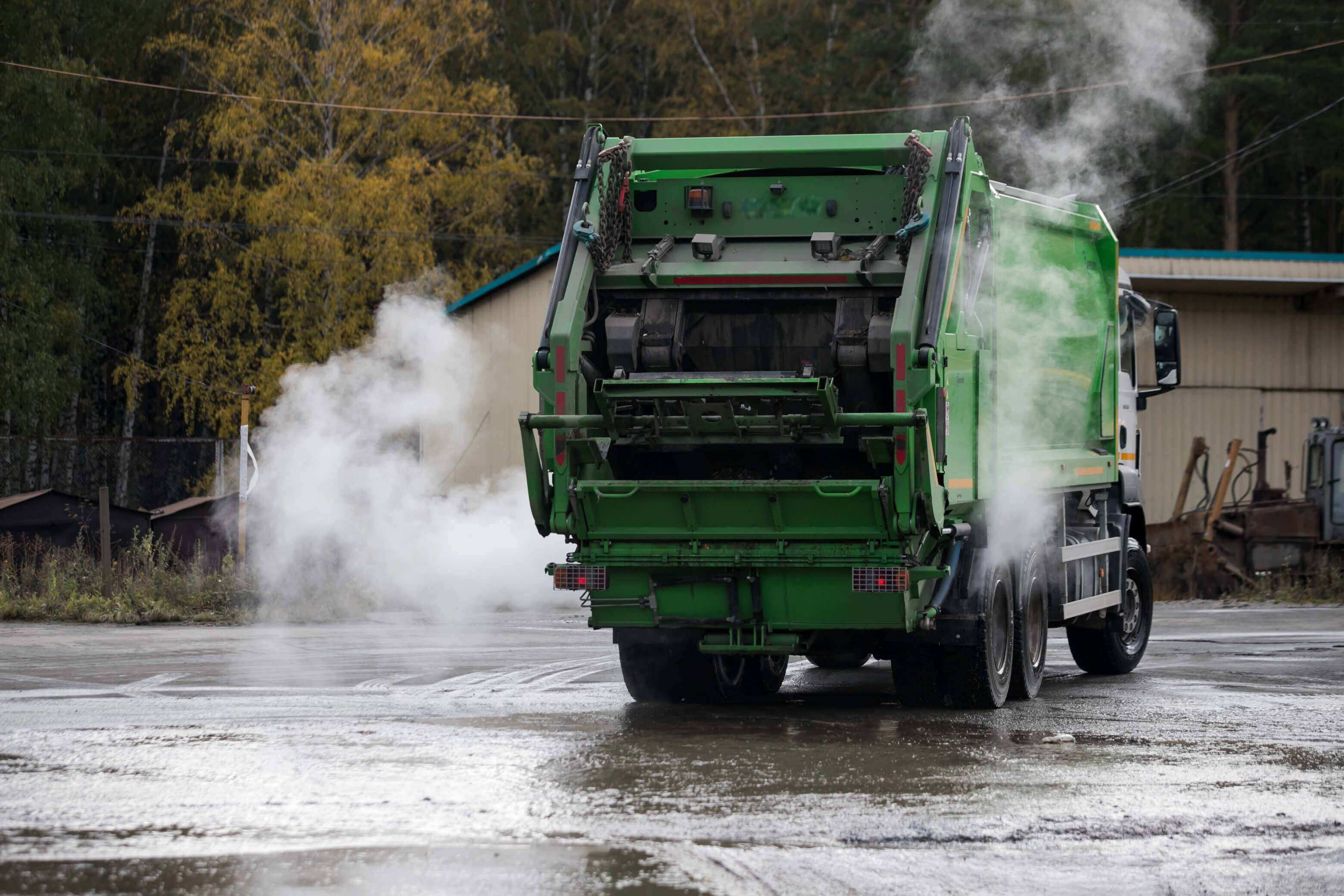 Green garbage truck smashing waste